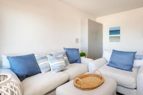 ein Wohnzimmer mit einem weißen Sofa und blauen Kissen in der Unterkunft Direct Oceanfront Studio Suite! in Hampton