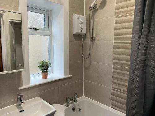 La salle de bains est pourvue d'une douche, d'un lavabo et d'une baignoire. dans l'établissement Homely 3 Bed House Halifax, à Exley