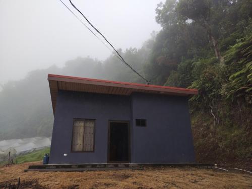 a small blue house on a hill in the fog at Mini casa, Vara Blanca in Heredia