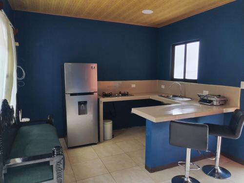 een keuken met blauwe muren en een koelkast bij Mini casa, Vara Blanca in Heredia