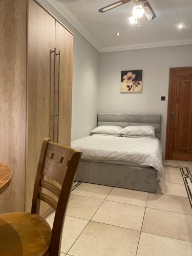 a bedroom with a bed and a table and a chair at North London Studio Apartment in London