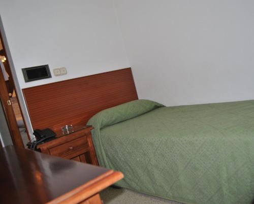 Habitación de hotel con cama y mesita de noche con cama sidx sidx sidx sidx en Hostal Blumen, en Algeciras