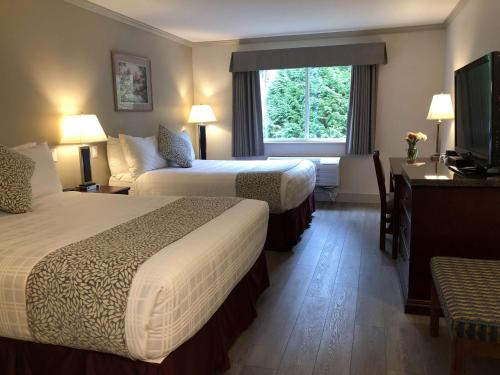 a hotel room with two beds and a television at Coast Abbotsford Hotel & Suites in Abbotsford