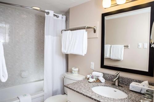 La salle de bains est pourvue d'un lavabo, de toilettes et d'un miroir. dans l'établissement Campus Tower Suite Hotel, à Edmonton