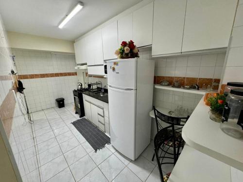 a kitchen with white cabinets and a refrigerator with flowers on it at Beira-mar na praia de pajuçara com Dois quartos - Apto 304 in Maceió