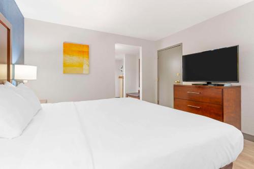 a white bedroom with a large bed and a flat screen tv at Comfort Inn Near Six Flags St Louis in Pacific