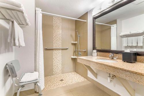 a bathroom with a shower and a sink and a chair at Comfort Inn Near Six Flags St Louis in Pacific