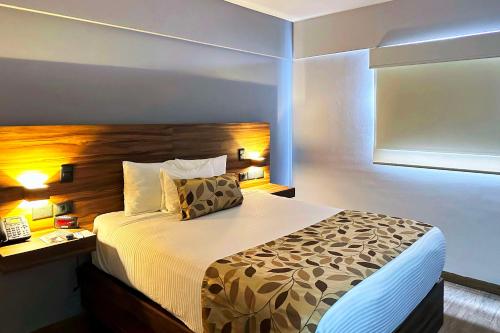a bedroom with a large bed with a wooden headboard at Sleep Inn Mazatlan in Mazatlán