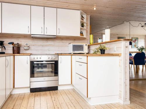een keuken met witte kasten en een magnetron bij 7 person holiday home in Juelsminde in Snaptun