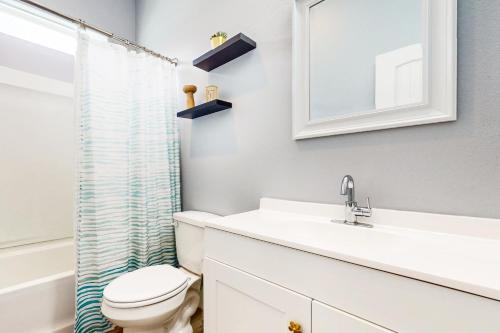 a bathroom with a toilet and a sink and a mirror at Hook Line and Sleeper in Rockport