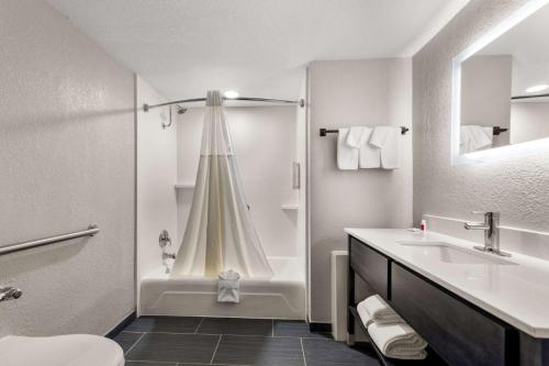 a white bathroom with a tub and a sink at Clarion Pointe Rhinelander Downtown in Rhinelander