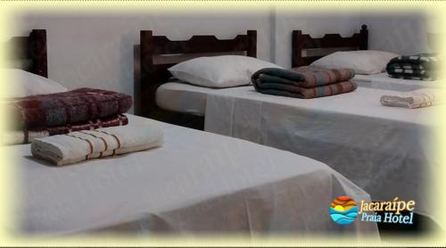 two beds with white sheets and pillows on them at Jacaraipe Praia Hotel in Serra