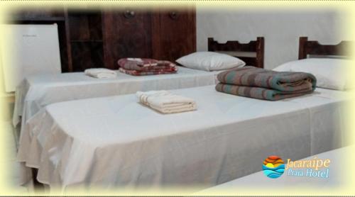 Jacaraipe Praia Hotel في سيرا: سريرين عليها شراشف بيضاء ومناشف