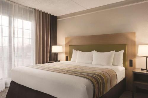 a hotel room with a large bed with white pillows at Country Inn & Suites by Radisson, Chicago-Hoffman in Hoffman Estates