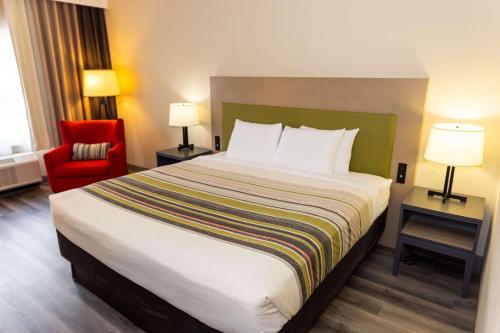 a hotel room with a large bed and a red chair at Country Inn & Suites by Radisson, Lehighton-Jim Thorpe, PA in Lehighton