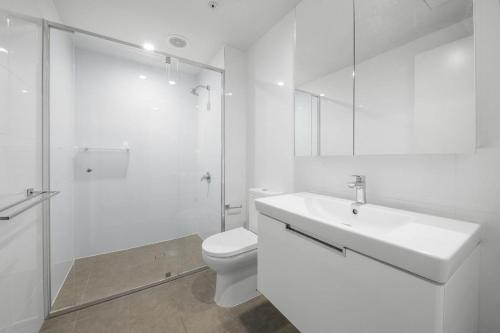 uma casa de banho branca com um lavatório e um WC em Arena Apartments South Brisbane em Brisbane