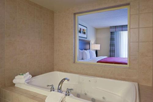 Un baño con bañera y un espejo grande. en Country Inn & Suites by Radisson, Fredericksburg, VA, en Fredericksburg