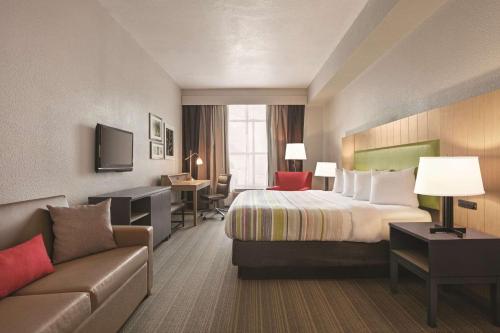 Habitación de hotel con cama y sofá en Country Inn & Suites by Radisson, Petersburg, VA, en Petersburg