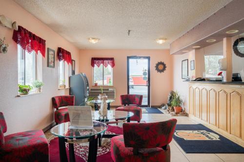 a living room with red chairs and a glass table at Super 8 by Wyndham Grants in Grants