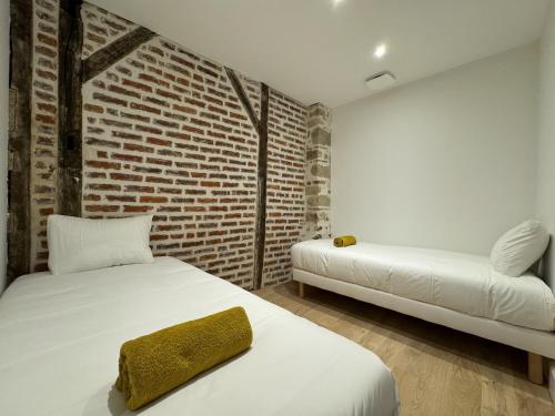 une chambre avec deux lits et un mur de briques dans l'établissement Le Corner - Ville - 8 pers - Rêve au Mans, au Mans