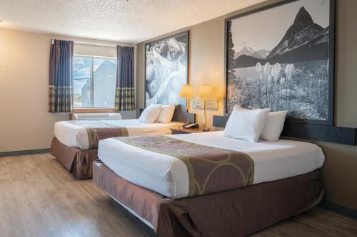 una camera d'albergo con due letti e un dipinto sul muro di Super 8 by Wyndham Grants a Grants