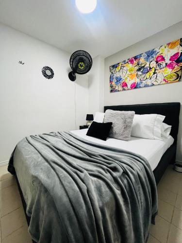 a bedroom with a large bed with a painting on the wall at Apartaestudio Encanto Pacífico in Cali
