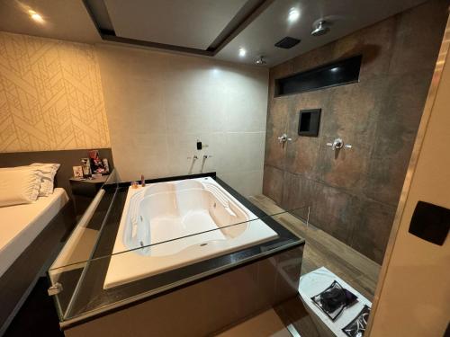 La salle de bains est pourvue d'une grande baignoire et d'une douche. dans l'établissement Prestige Motel 3, à São Paulo