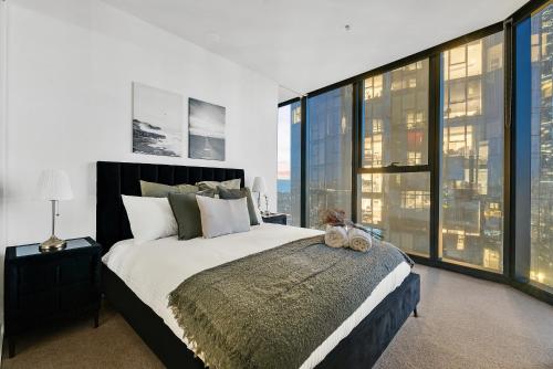 a bedroom with a large bed and large windows at Melbourne Square Apartments in Melbourne
