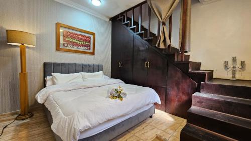a bedroom with a bed with white sheets and a staircase at Peaceful in Heart of El mansoura in Mansoura