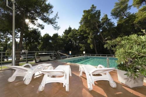 - un groupe de chaises blanches à côté de la piscine dans l'établissement Apartments with a swimming pool Podstrana, Split - 20098, à Podstrana