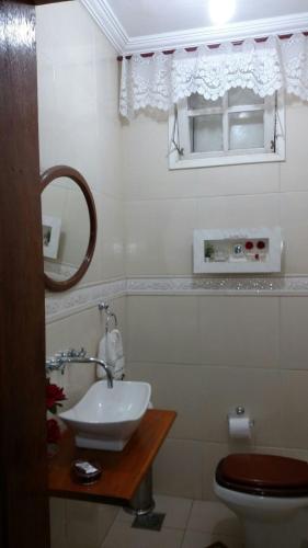 a bathroom with a sink and a toilet and a mirror at Pousada Jupter in Teresópolis