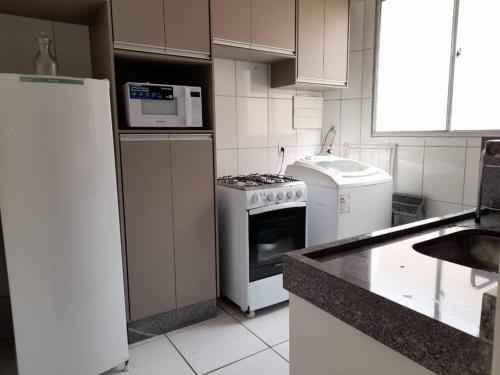een keuken met een fornuis en een magnetron bij Apartamento Completo - Res Pq Humanita - Bl 02 in Uberlândia