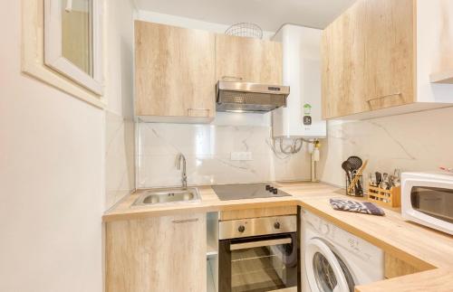 une petite cuisine avec un évier et un micro-ondes dans l'établissement 25m2 Cosy Proche Métro 11 - 6 min à pied, aux Lilas