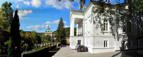 a white building with a car parked in front of it at Villa Patriot Boutique Hotel in Mariánské Lázně