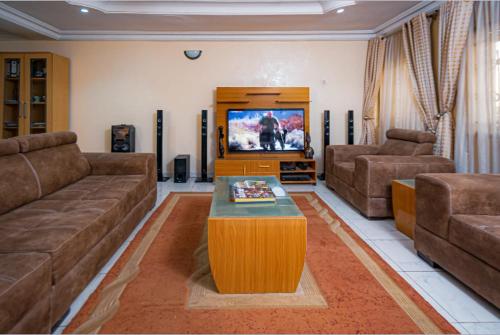 a living room with a couch and a tv at Checkers Suite & Apartments in Abuja