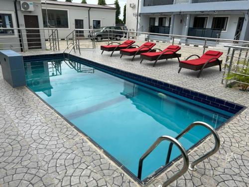 a swimming pool with red chairs at Checkers Suite & Apartments in Abuja