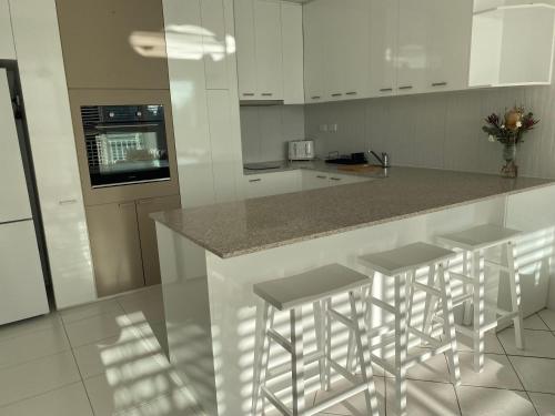 a kitchen with white cabinets and a counter with stools at Condor Surfers - Hosted by Coastal Letting Company in Gold Coast