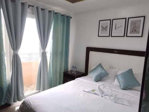 a bedroom with a bed with green curtains and a window at Robinson manila birchtower in Manila