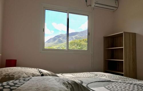 a bedroom with a window with a view of a mountain at Gite Le Panoramique in Dumbéa