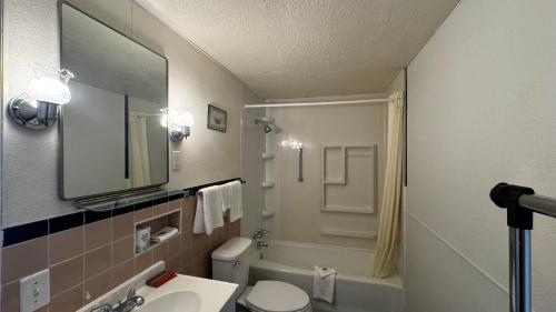 a bathroom with a sink and a toilet and a mirror at Hopwood Motel in Uniontown