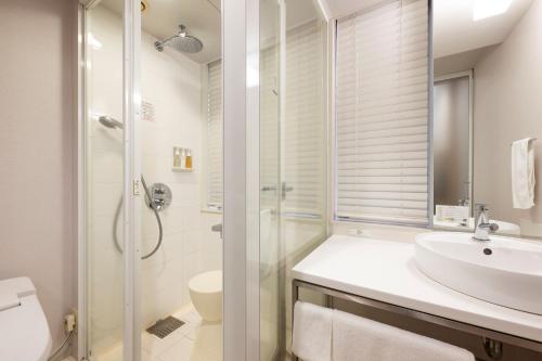 a bathroom with a sink and a shower at remm Hibiya in Tokyo