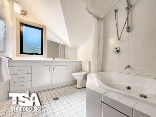 ein weißes Badezimmer mit einer Badewanne und einem Waschbecken in der Unterkunft Pagano 4 in Thredbo