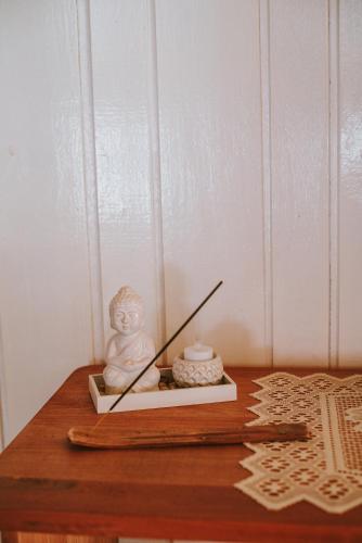 a statue on a table with a candle and chopsticks at Morada encanto da cachoeira in Aguas Mornas