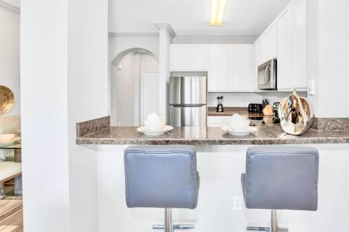 a kitchen with two blue chairs at a counter at Upscale 3BR Near Disney - Pool and Hot Tub! in Orlando