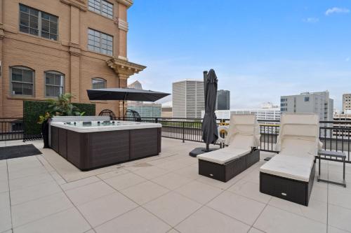 a hot tub on a patio with chairs and an umbrella at The Eleanor New Orleans in New Orleans
