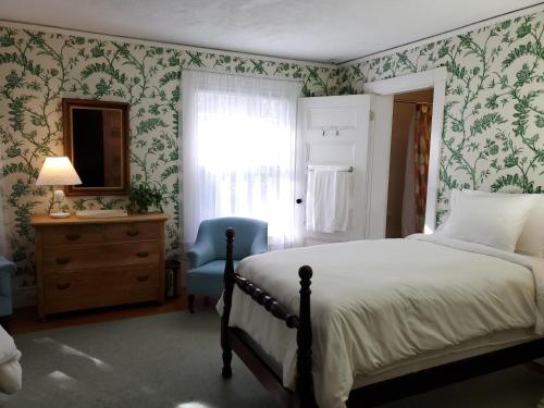 a bedroom with a bed and a chair and a window at Harbourside Inn in Northeast Harbor