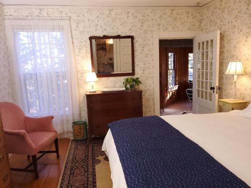a bedroom with a bed and a chair and a mirror at Harbourside Inn in Northeast Harbor