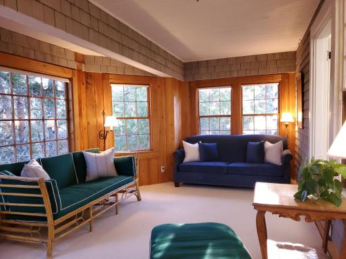 a living room with two blue couches and windows at Harbourside Inn in Northeast Harbor