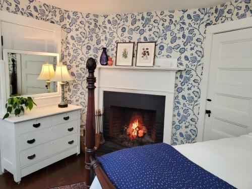 a bedroom with a fireplace with blue and white wallpaper at Harbourside Inn in Northeast Harbor