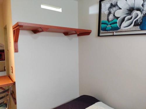 a bedroom with a white wall with a picture on the wall at bonito mini depto. equipado Futurista in Atlacomulco de Fabela